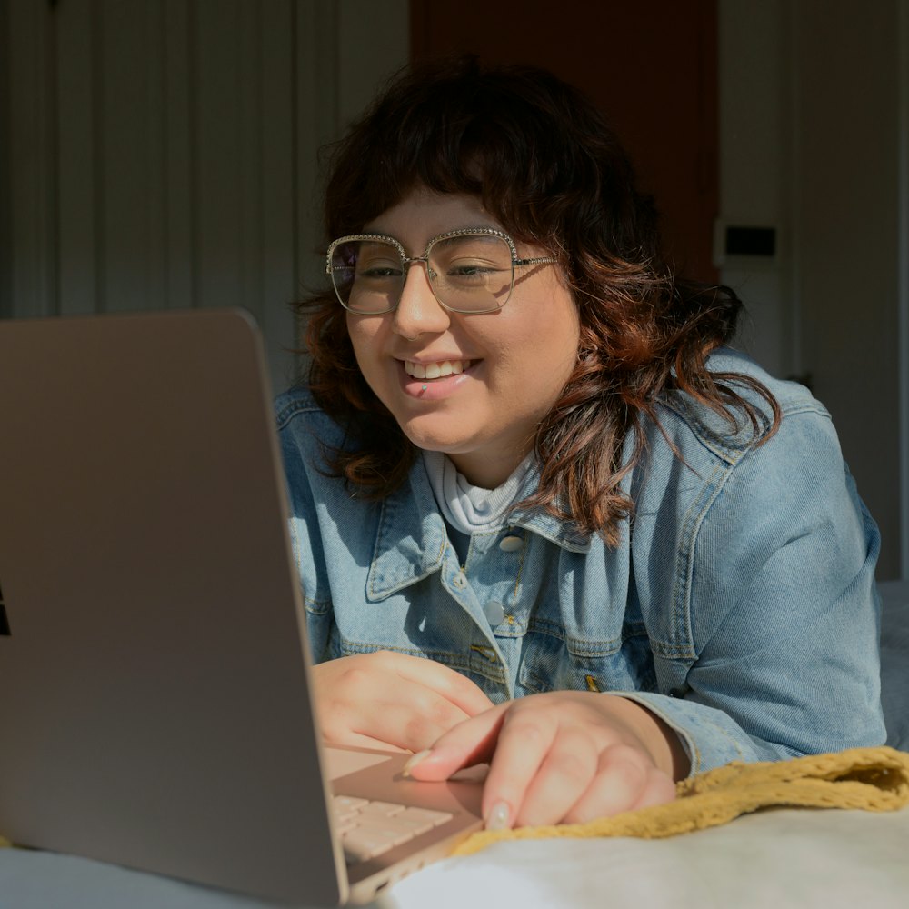 Mulher sorrindo diante do notebook, numa chamada de vídeo em casa