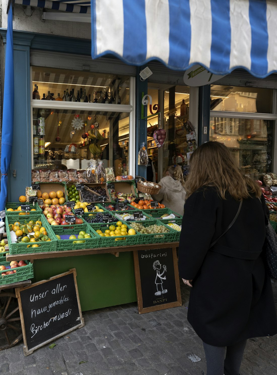 Mulher escolhendo frutas e legumes na banca de um mercado de rua